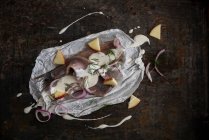 Filetes de arenque con salsa de yogur, trozos de manzana, chalotes y eneldo sobre papel pergamino - foto de stock