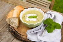 Leek and potato soup with cream, mint and crusty baguette — Stock Photo