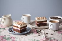 Cappuccino-Kuchen mit Schokoladenbiskuit und Vanille-Zuckerguss serviert mit Kaffee — Stockfoto