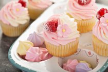 Cupcakes de vainilla y frambuesas con glaseado de queso crema y flores de azúcar - foto de stock