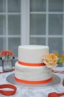 Un pastel de boda de dos niveles decorado con rosas - foto de stock