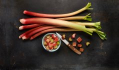 Rhubarb stems and chopped rhubarb in a bowl with a knife — Stock Photo