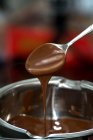 Geschmolzene Schokolade tropft von einem Löffel in eine Schüssel — Stockfoto