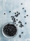 Black beans in a glass bowl and next to it — Stock Photo