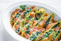 Pastas de cáscara con espinacas y ricotta relleno en salsa de tomate con parmesano - foto de stock