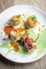 Roasted wild rabbit with crispy bacon and stuffed rice balls arancini and a sweet green pea sauce and gravy — Stock Photo