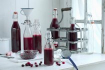 Cornelian cherry syrup in bottles on a kitchen table — Stock Photo