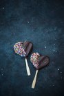 Biscoitos vegan em forma de coração em paus cobertos com chocolate escuro e polvilhas — Fotografia de Stock