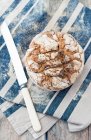 Хліб домашнього кислого хліба на тканині поруч з мішком борошна і ножем — стокове фото