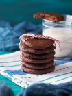 Stack of home made chocolate cookies with red twine over green background — Stock Photo
