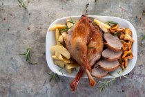Goose legs and breast with chanterelle mushrooms and roast potatoes — Stock Photo