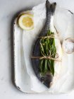A whole sea bream with wild garlic on baking paper — Stock Photo