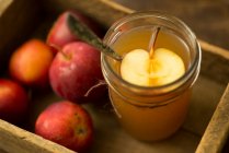 Склянка сидру з половиною яблука і цілих яблук в дерев'яній ящиці — стокове фото