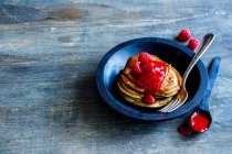 Nahaufnahme von frisch zubereiteten Pfannkuchen mit Himbeermarmelade und frischen Himbeeren in rustikaler Holzschüssel zum Frühstück — Stockfoto