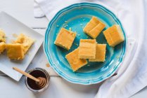 Pan de maíz en un plato azul y miel - foto de stock