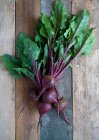 Several fresh beetroots with leaves on a wooden background — Stock Photo