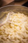 A cook preparing pasta and cheese sauce for making macaroni cheese — Stock Photo