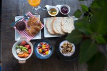 Сніданок з фруктовим салатом, йогуртом та мюслі, круасан, білий хліб та варення — стокове фото