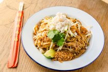 Pad thai stir fried noodles with prawns, chilli, beans, sprouts, spring onions, carrots, crab meat, shredded apple, lime and peanut — Stock Photo