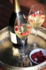 Bottle and two glasses of champagne with wild strawberries on silver tray — Stock Photo