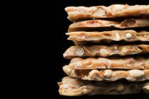Stack of peanut brittle on a black background (close-up) — Stock Photo