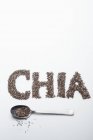 Sementes de chia: em uma colher e letrado contra um fundo branco — Fotografia de Stock