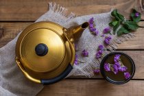 Um bule e xícara de chá verde com hortelã e flores comestíveis — Fotografia de Stock