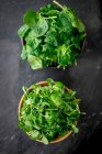Spring spinach and watercress in wooden bowls — Stock Photo