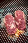 Raw ribeye steaks on a grill — Stock Photo