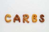 Carbs spelled out with bread basket goodies — Stock Photo