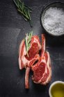 Two fresh lamb chops, sea salt flakes, olive oil and rosemary — Stock Photo