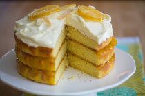 Un pastel de limón de tres capas con glaseado y limones confitados - foto de stock