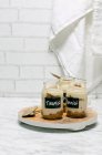 Индивидуальные десерты тирамису в банках с ложками на деревянной доске — стоковое фото