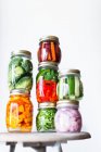 Preserving jars of freshly pickled vegetables stacked on an old stool — Stock Photo