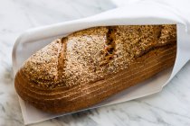 Un pain complet rustique dans une serviette — Photo de stock