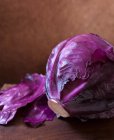 Целая голова фиолетовой капусты на доске для резки дерева — стоковое фото