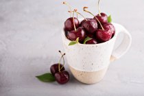 Cerezas dulces frescas en una taza de cerámica - foto de stock