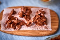 Cornflakes covered in chocolate on wooden board — Stock Photo