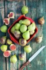 Fresh figs in red crate and on rustic wooden surface with knife — Stock Photo