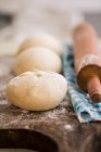 Balls of pizza dough with a rolling pin on a wooden board — Stock Photo