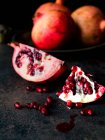 Ripe pomegranate and seeds on a dark background — Stock Photo