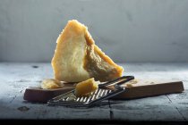 Grana Padano em tábua de madeira com ralador de queijo — Fotografia de Stock