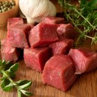 Carne cruda cortada en cubos con ajo y hierbas - foto de stock