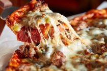 Пицца с колбасой и сыром, нарезанный — стоковое фото
