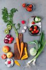 Ein Arrangement aus Frühlingszwiebeln, Knoblauch, Äpfeln, Tomaten, Paprika, Karotten, Kiwi, Radieschen, Erdbeeren und Kohlrabi — Stockfoto