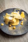 Gâteau au fromage Persimon avec une purée de persimon et des chips sur une assiette noire et un fond en bois clair — Photo de stock