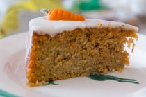 A slice of carrot cake with icing and marzipan carrots — Stock Photo