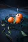 Fresh mandarins with leaves in wire basket — Stock Photo