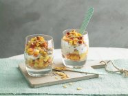 Fruits et yaourts aux flocons de maïs et graines dans des verres — Photo de stock