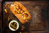 Ein Hot Dog mit Ketchup, Senf und gebratenen Zwiebeln, serviert auf einem alten Backblech — Stockfoto